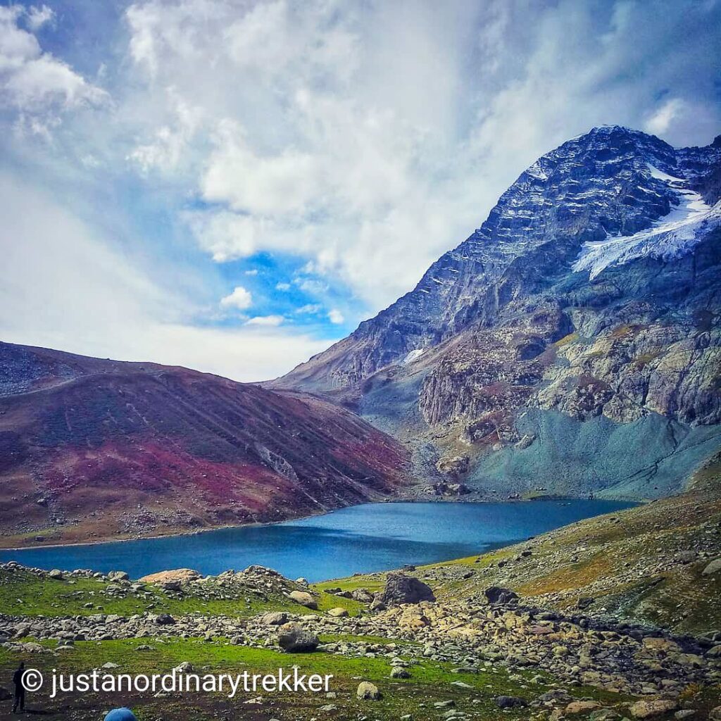View of Nundkol Lake from the trail to Naranag on the Kashmir Great Lakes Trek, surrounded by towering Himalayan peaks and lush meadows.